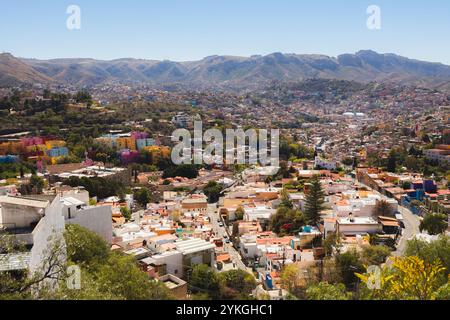 A vibrant panoramic view of Guanajuato, Mexico, with colorful buildings sprawling across hillsides under a bright, sunny sky. Stock Photo