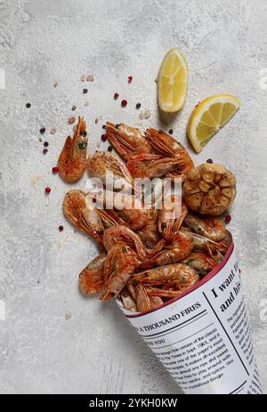 Fried shrimp, in a paper bag, shrimp for beer, in a newspaper, on a gray table, no people Stock Photo