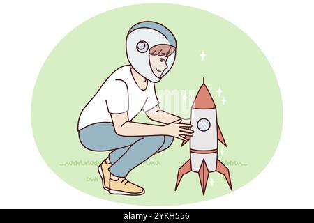 Little boy squatting near toy rocket representing launching spaceship to another planet. Child plays as astronaut, wanting to work in space industry a Stock Photo