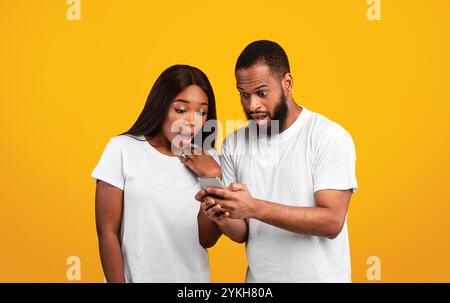 Portrait of surprised black couple using smartphone Stock Photo