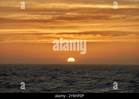 The sun sets beautifully over the horizon in the sea. Stock Photo