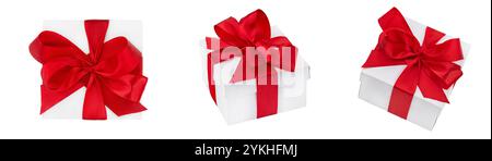 Set of three white gift boxes with red bows from satin ribbon at different angles on white isolated background with clipping path. Element for design. Stock Photo