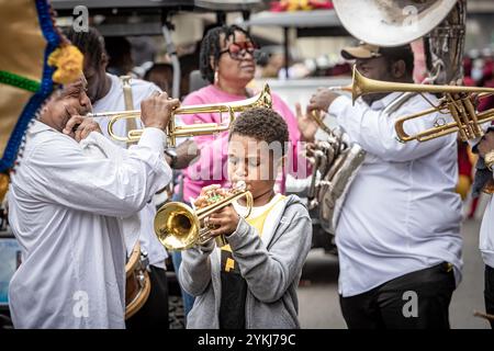 Young trumpet player blows his horn with other musicians in the Second Line parade moving through the streets of the Treme neighborhood in New Orleans Stock Photo