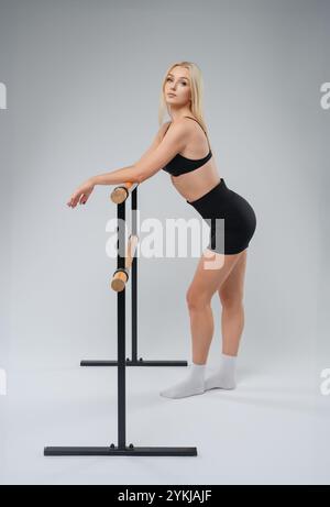 Young dancer practicing at the ballet barre in a studio during afternoon light Stock Photo