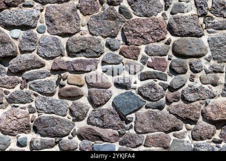 Old dark rough stone wall, background photo texture, front view Stock Photo