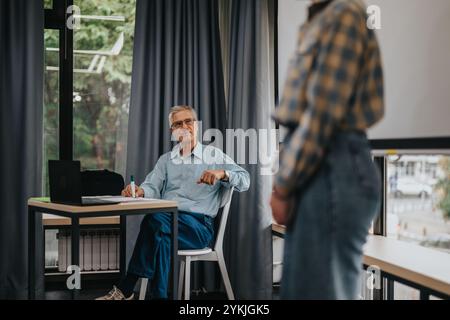 Elderly professor engaging with students in a modern classroom Stock Photo