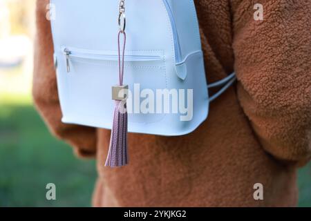 Woman with pink leather keychain on her backpack outdoors, closeup Stock Photo