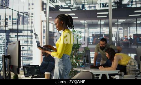 System administrator creating machine learning models that can process and analyze data to automate decision making processes. IT staff member using laptop to do programming in office, camera B Stock Photo