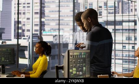 Machine learning infrastructure technicians using tablet to do checkup on algorithms that enable machines to learn from data. Coworkers in office training deep learning models using device Stock Photo