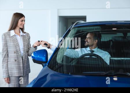 Saleswoman giving key to client inside new car in salon Stock Photo - Alamy