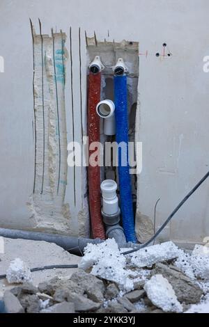 Plumbing installation in progress with red and blue water pipes embedded in a wall during home renovation Stock Photo