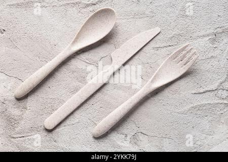 A recycled plastic spoon, knife and fork are seen on a gray cement surface Stock Photo