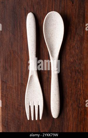 A recycled plastic spoon and fork is seen on rustic wood Stock Photo