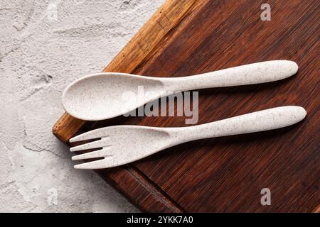 A recycled plastic spoon and fork is seen on rustic wood Stock Photo