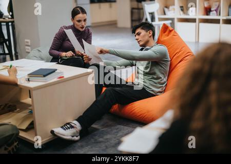 Students collaborating in a modern classroom environment on a cozy bean bag chair, discussing project ideas and sharing educational materials Stock Photo