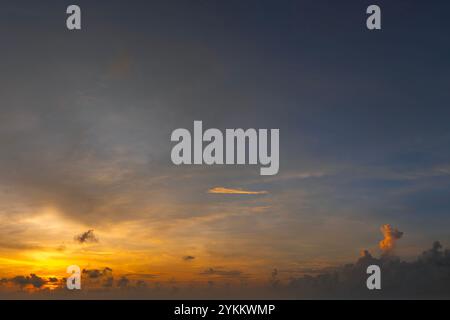 Bright sunset with setting sun behind vivid orange and yellow clouds Stock Photo