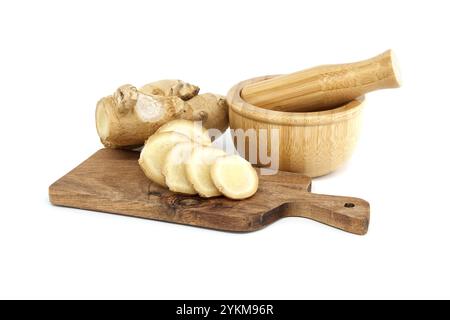 Fresh ginger root displayed on a wooden cutting board with slices, alongside a bamboo mortar and pestle, isolated on white background Stock Photo