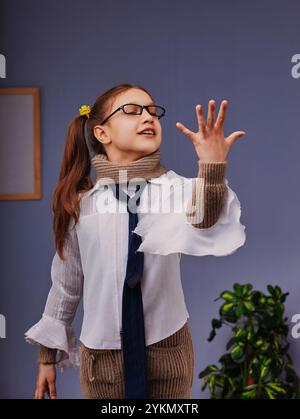 Elementary school student wearing glasses and a tie explores a virtual reality environment, reaching out with her hand and showing curiosity on her fa Stock Photo