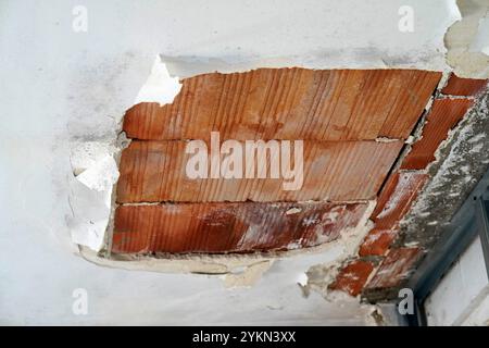 ceiling chipped due to humidity, showing bricks and mold. Stock Photo