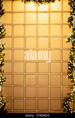 Window made of glass vintage blocks with yellow light, decorated with a garland of Christmas trees and lights Stock Photo