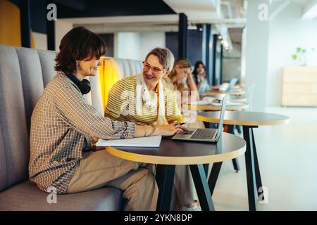 A dynamic scene of students collaborating and sharing ideas on a campus, enjoying the vibrant educational atmosphere with laptops and notes. Stock Photo