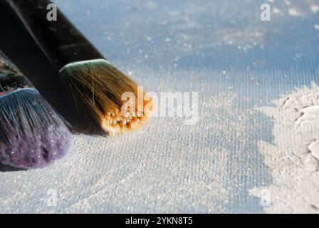 Colorful painting brushes of various sizes placed on a vibrant acrylic paint background. Stock Photo