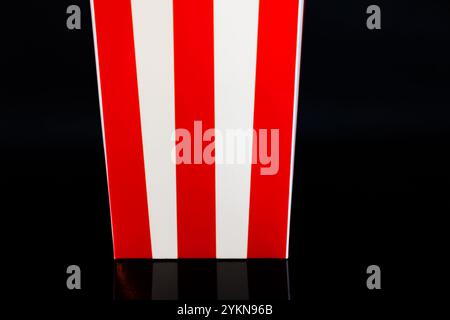 Cardboard bucket of popcorn reflected on a black background, cinema and popcorn concept Stock Photo
