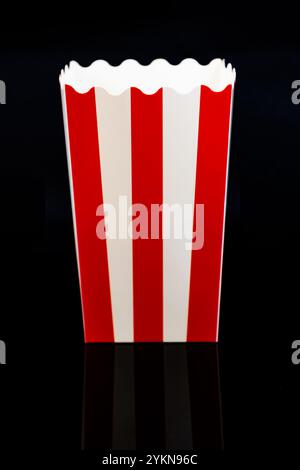 Vertical image of cardboard popcorn bucket reflected on a black background, cinema and popcorn concept Stock Photo