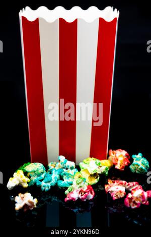 Vertical image of cardboard bucket with colorful popcorn reflected on a black background, cinema and popcorn concept Stock Photo