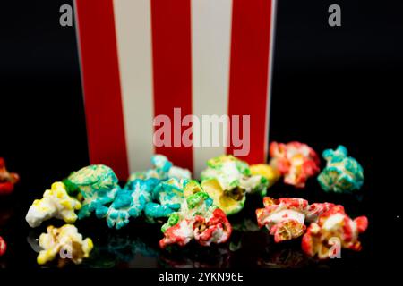 Horizontal image of cardboard bucket with colorful popcorn reflected on a black background, cinema and popcorn concept Stock Photo