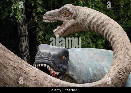 A close up of a dinosaur sculpture in a park, showcasing its detailed design, vibrant colors, and lifelike appearance, blending creativity with paleon Stock Photo