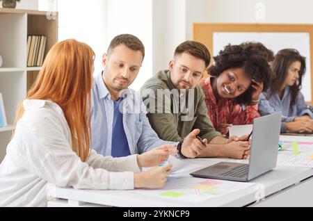 Diverse group of colleagues working together on project, discussing tasks and preparing presentation Stock Photo