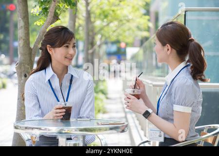 Two office workers drinking iced coffee outdoors Stock Photo