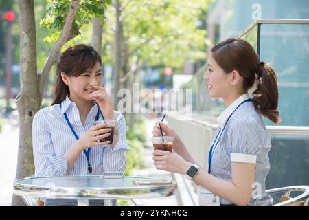 Two office workers drinking iced coffee outdoors Stock Photo