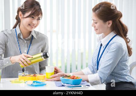 Two office workers eating lunch in office Stock Photo