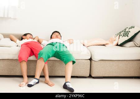 Brothers of schoolchildren playing and laughing while lying on the sofa Stock Photo