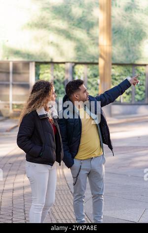 Young man pointing to something interesting while exploring a city with his girlfriend Stock Photo