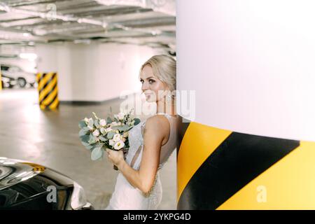 The bride in the underground Parking stands near the parked car Stock Photo