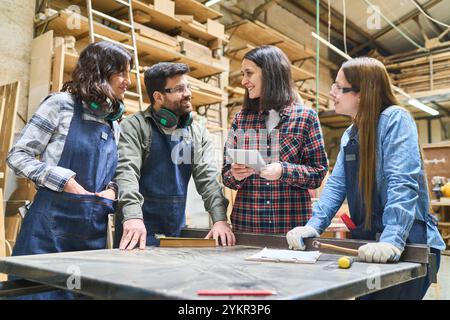 Diverse group of workers collaborating in a lumberyard, focusing on teamwork and training. A blend of experienced and younger individuals engaging in Stock Photo