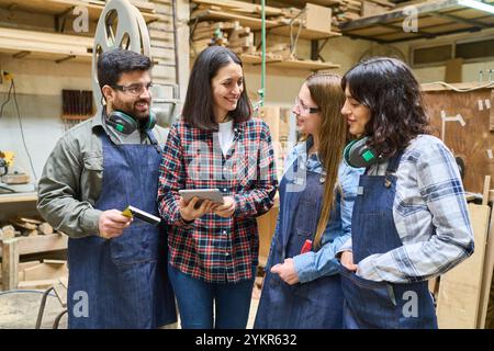 A diverse group of people engaging in collaborative work in a woodworking workshop. The image highlights training, teamwork, and a supportive learning Stock Photo