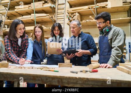A diverse group working collaboratively in a lumberyard, focusing on woodworking tasks. The scene includes workers of different ages, highlighting tea Stock Photo