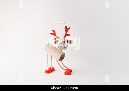 DIY reindeer puppet made from cardboard tubes, red plastic caps, and paper details. Studio shot on a white background. Christmas craft and holiday dec Stock Photo