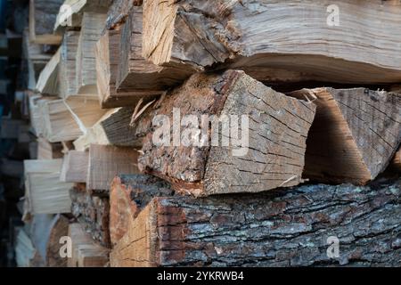 Pile of split wood stacked crosswise, chopped firewood with wood and bark texture closeup Stock Photo