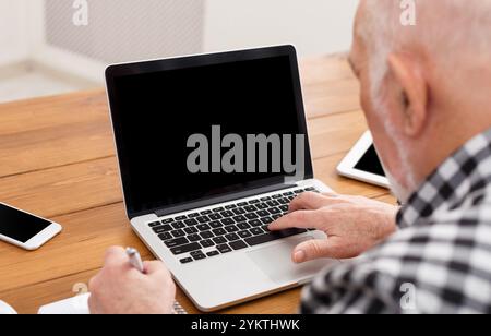 Senior man using laptop with blank screen mockup Stock Photo