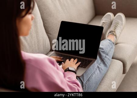 Woman using laptop with blank mockup screen, typing on keyboard Stock Photo