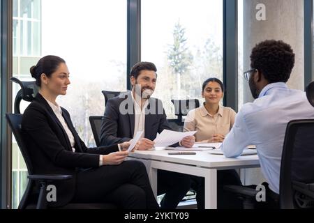 Corporate team engaged in business meeting around office table. Professionals discussing project strategy with focus on collaboration. Teamwork and leadership in modern office environment. Stock Photo