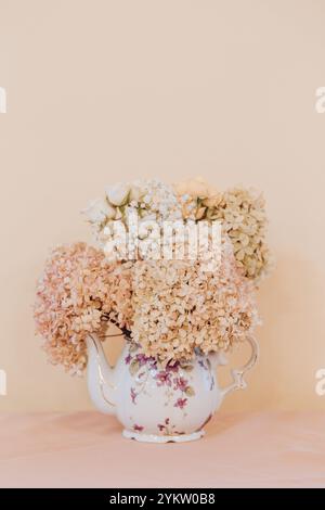 Pink Teapot Vase with Dried Hydrangea and Roses Background still life Stock Photo