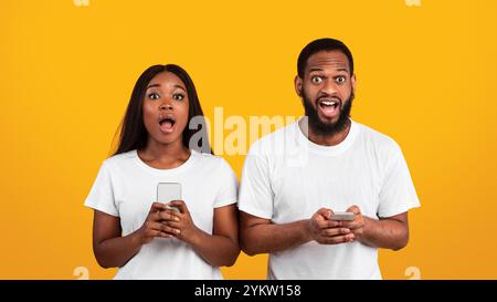 Portrait of surprised black couple using smartphones Stock Photo