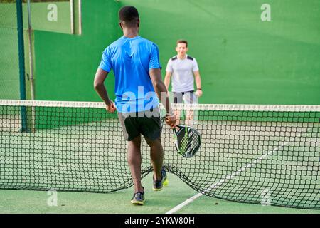 Two young friends playing paddle tennis on a court. Sports concept. Copy space Stock Photo