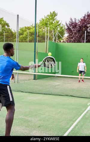 Two young friends playing paddle tennis on a court. Sports concept. Copy space Stock Photo